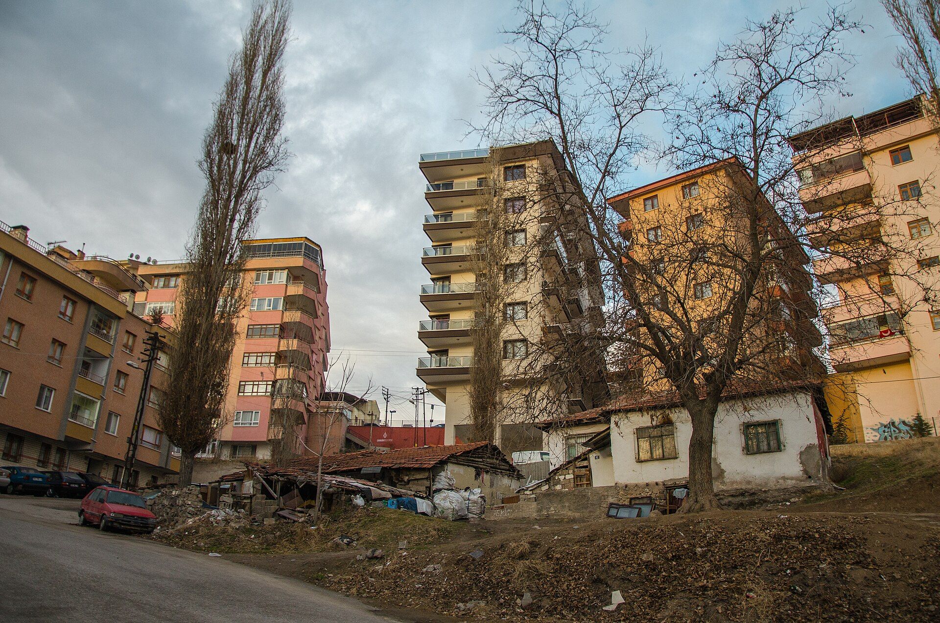 Mamak’ta yokuş bir sokak: kavaklar, eski bir gecekondu ve arkasında sıvası solmuş yüksek apartmanlar